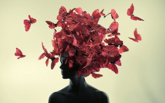 Donna con delle farfalle rosse sulla testa pensare positivo